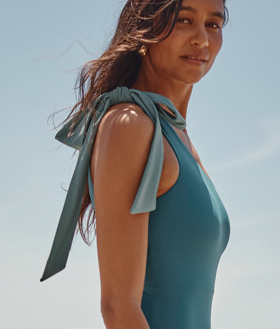 Model in blue bow-topped one piece swimsuit