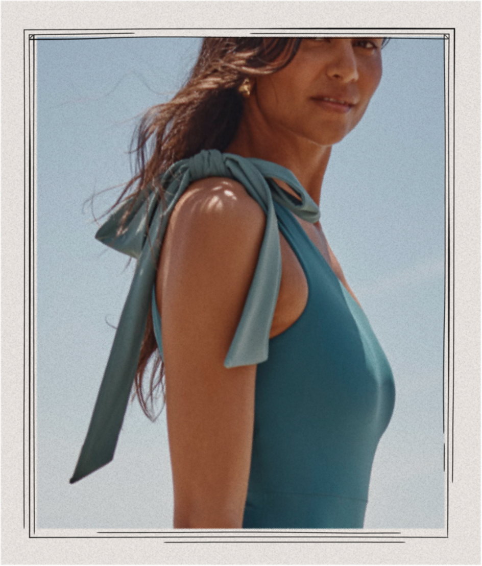 Model in blue bow-topped one piece swimsuit