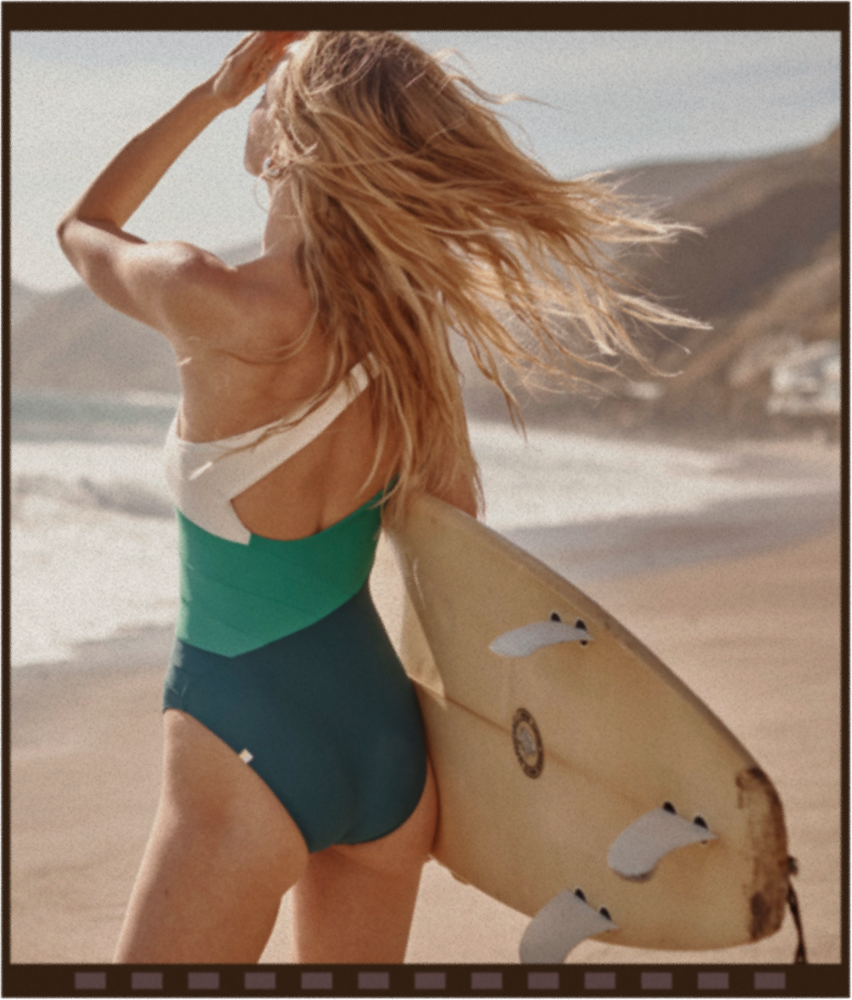 Model in green, blue and white one piece swimsuit