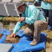 An NRCS soil scientist demonstrates soil health concepts with soil samples during a field day.