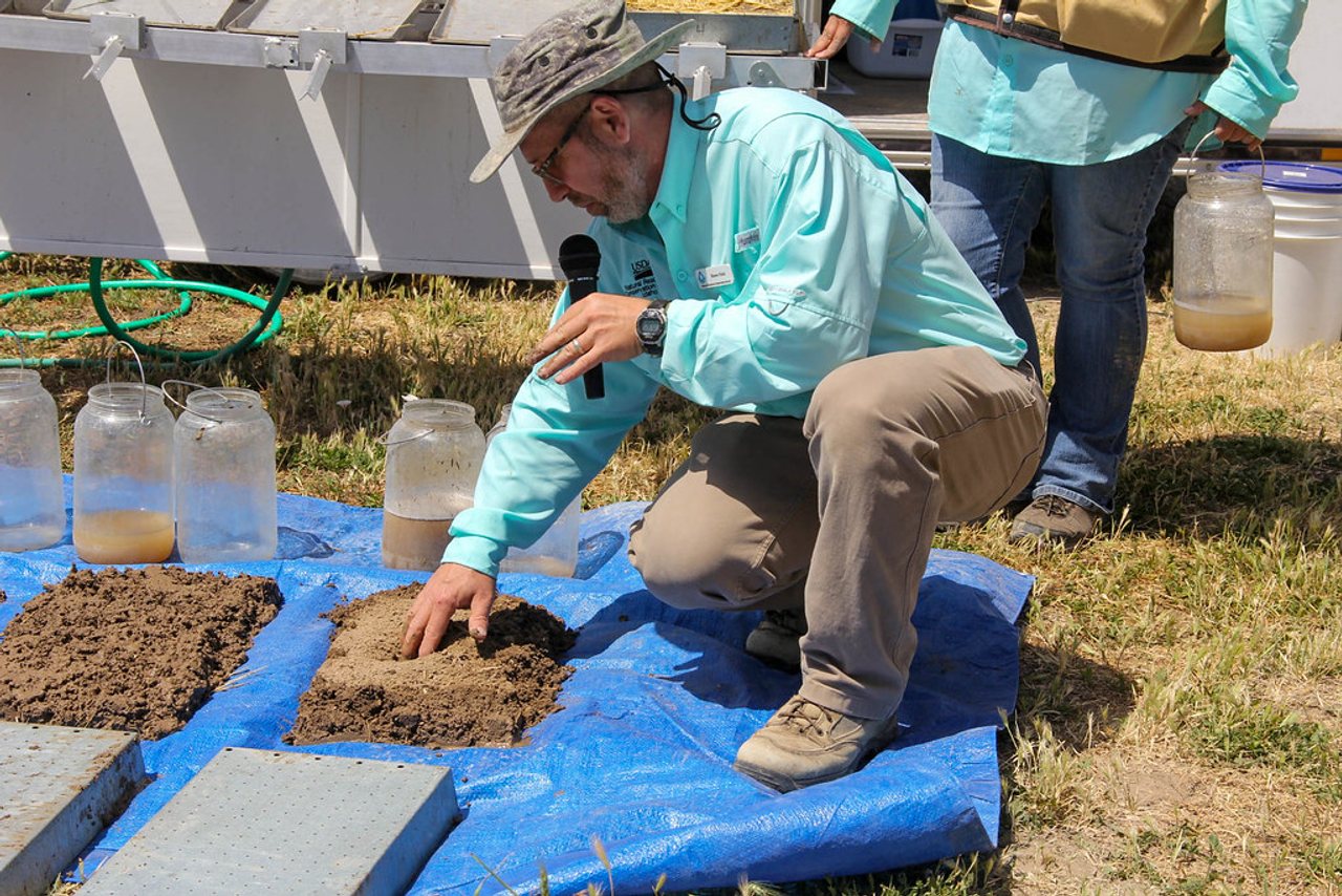 An NRCS soil scientist demonstrates soil health concepts with soil samples during a field day.