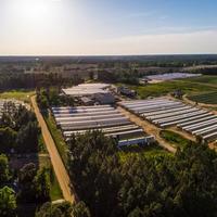 Aerial view of a diversified Georgia farm with greenhouses, vegetable plots, field crops, trees, and surrounding woodland