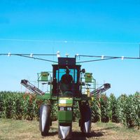 A high-clearance nitrogen applicator fitted with crop-canopy sensors stands in front of a green corn field.