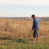 A farmer working by hand in a dry field.