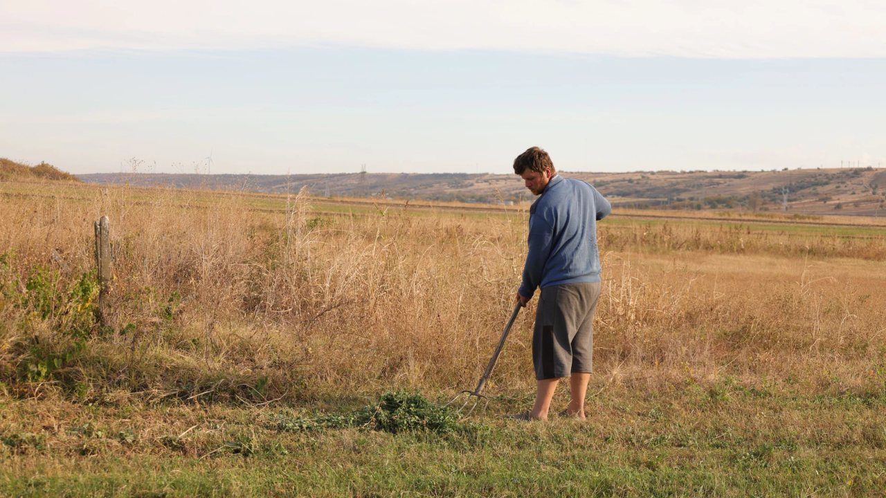 A farmer working by hand in a dry field.