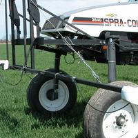 A field applicator fitted with light-reflectance sensors moves through a green crop field.