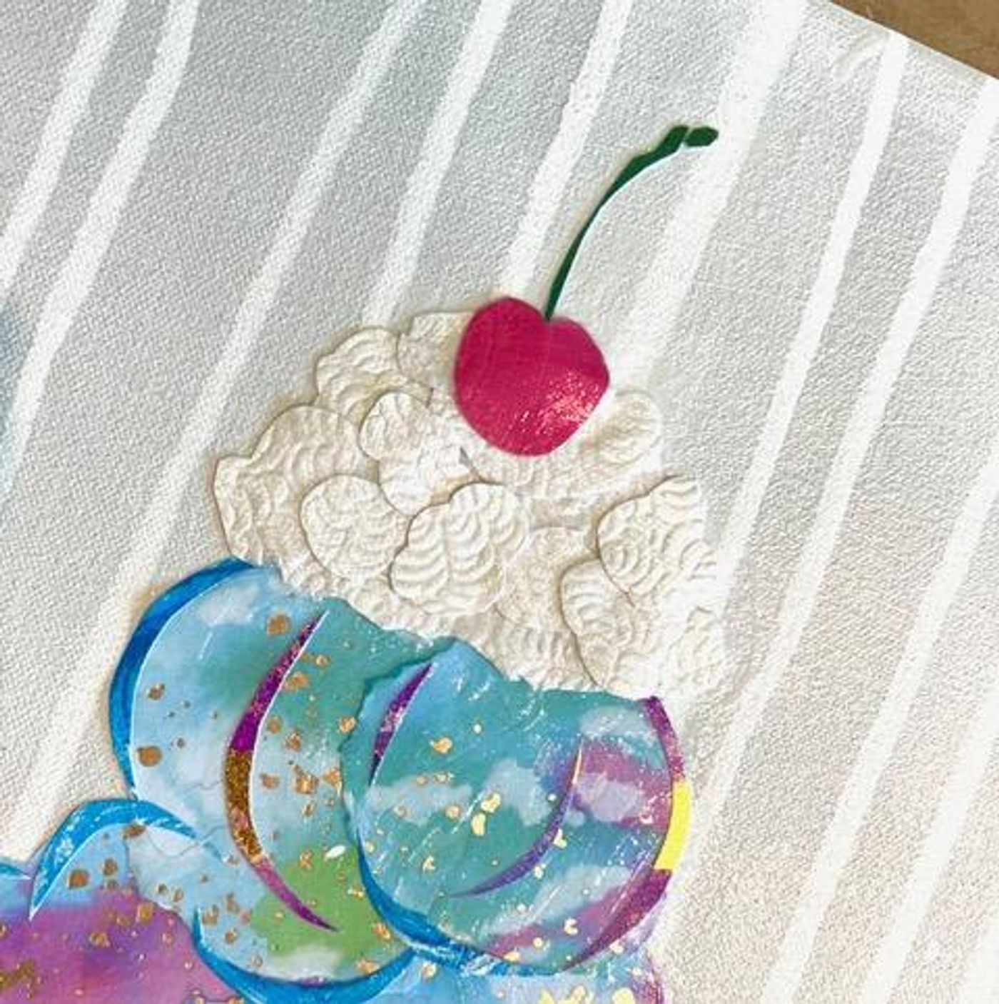 Close-up of the ice cream collage's top — textured white paper whipped cream, a red cherry, and an iridescent blue scoop.