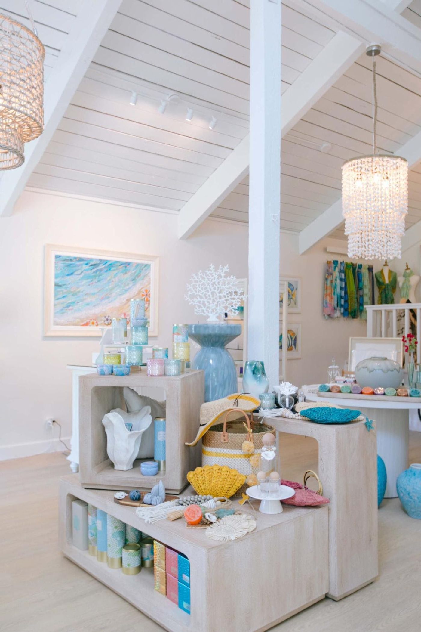 Inside Island Pearl on Sanibel — whitewashed tables of candles and coastal goods, shell chandelier, beach art on the wall