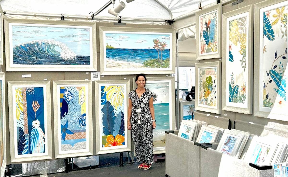 Jennifer in her studio holding two new abstract floral collages, one with an orange dahlia, one with pink hibiscus blooms