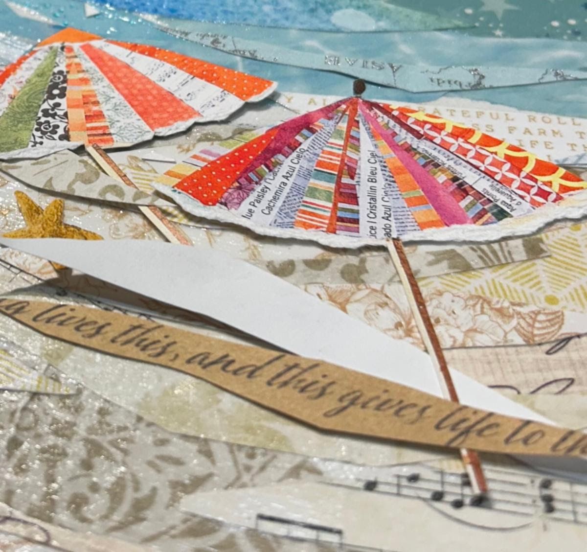 Detail of paper beach umbrellas over sandy patterned papers, with a starfish and a strip of handwritten script