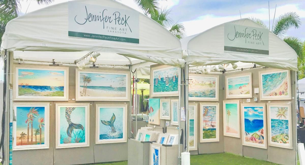 Jennifer Peck Fine Art booth — two white festival tents hung with framed coastal collages on gray walls, palms overhead