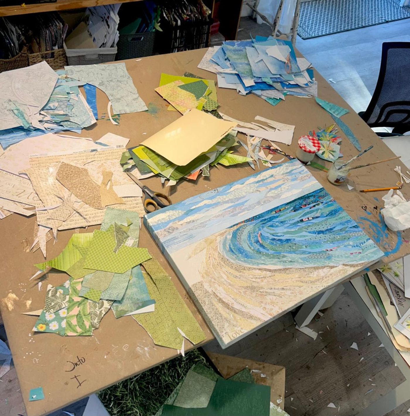 Jennifer's worktable buried in cut-paper scraps, "Sunny Days" taking shape at one corner beside scissors and glue