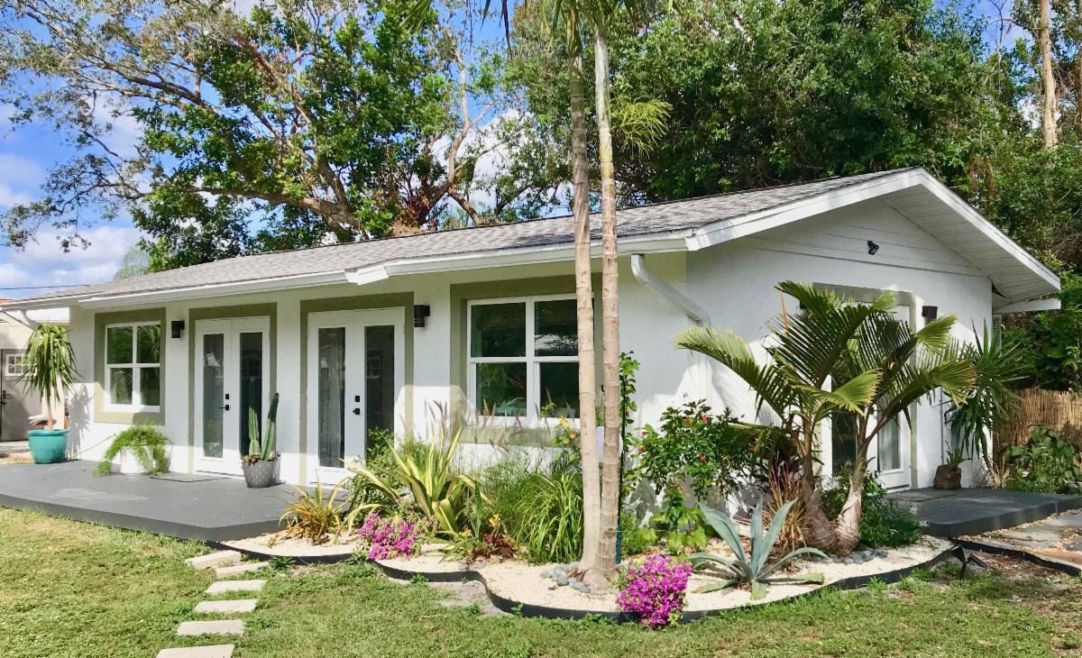 The new studio at 3634 Beacon Lane, a white cottage with sage trim and fresh tropical landscaping