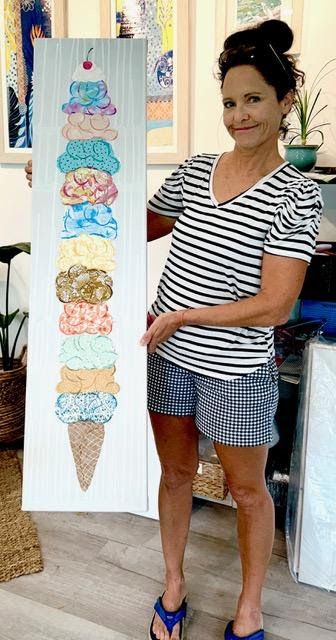 Jennifer in her studio holding the tall narrow ice cream collage — a dozen patterned paper scoops stacked on a cone, cherry on top.