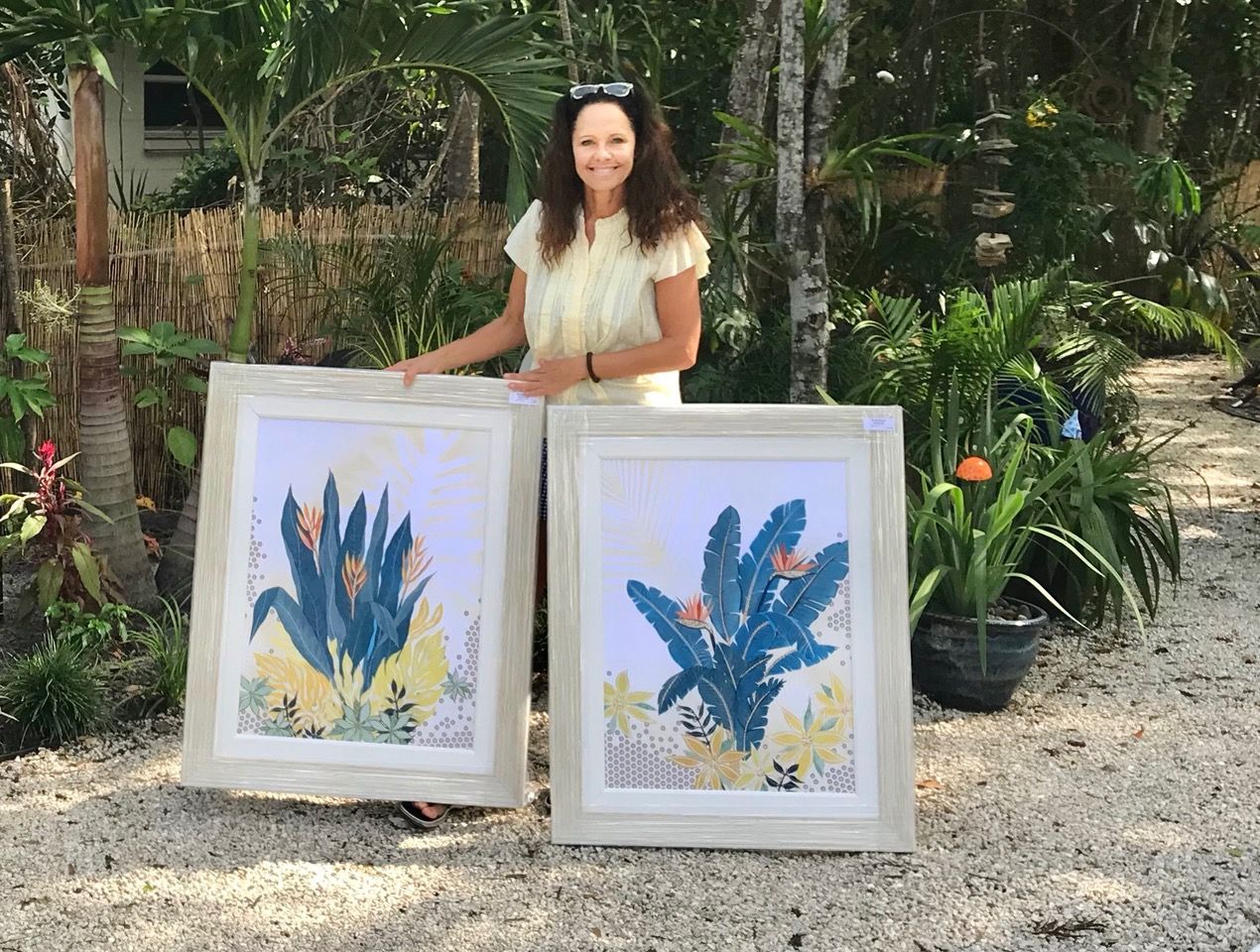 Jennifer in her tropical garden with the framed botanical collages Wild Blue Yonder and My Blue Heaven