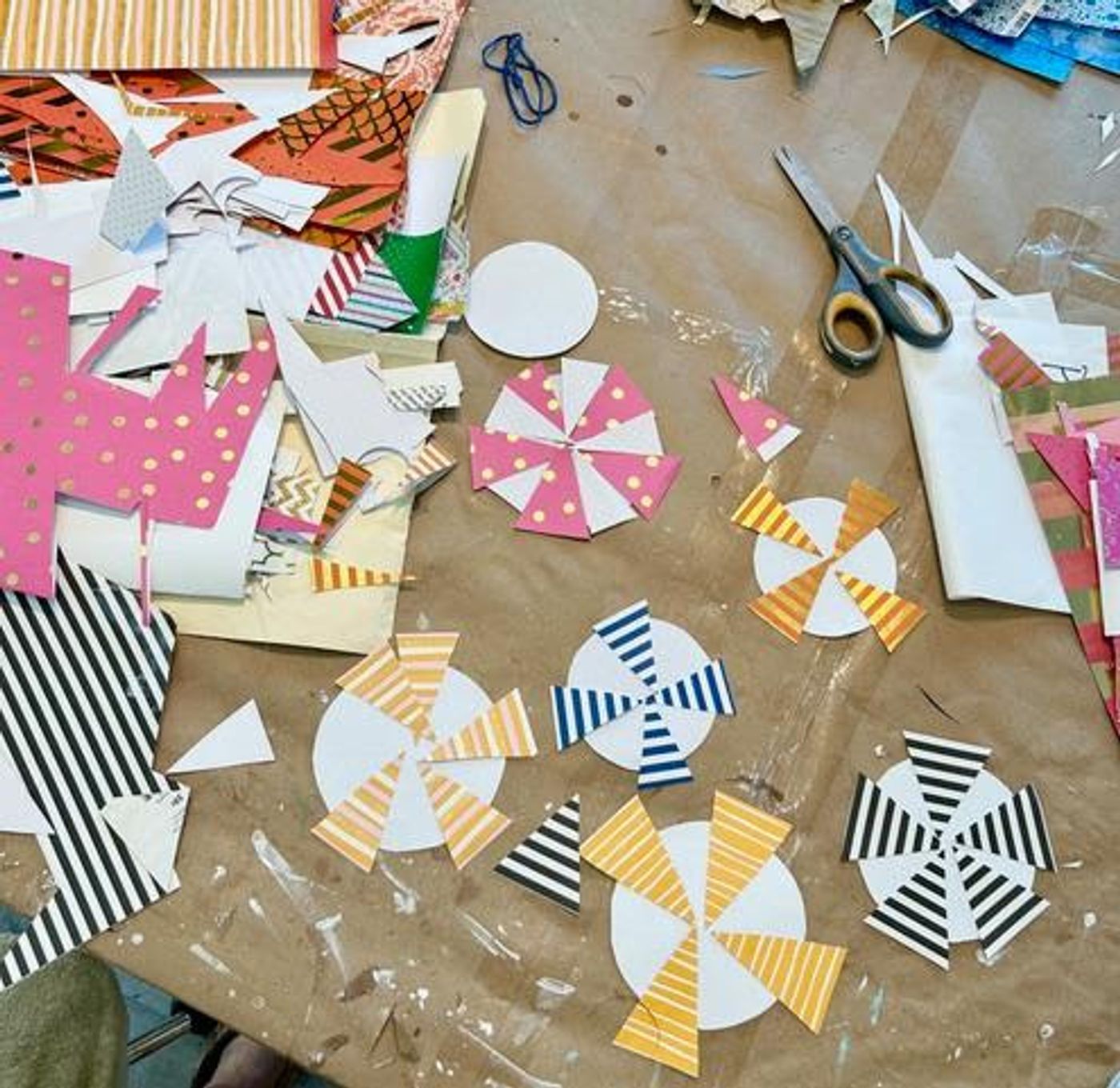 Striped paper beach-umbrella tops cut out and laid across the kraft-covered work table, scissors at the ready.