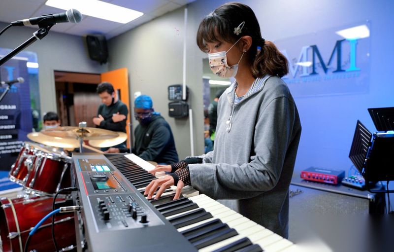 An MMI student plays keyboard alongside bandmates during a music mentorship session.