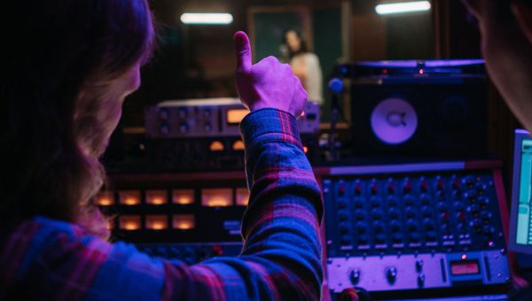 A mentor behind studio equipment gives a student a thumbs up during a youth music program in Nashville.