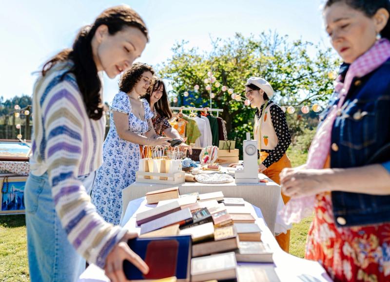 Festival attendees browsing books, handmade items, and vendor displays outdoors.