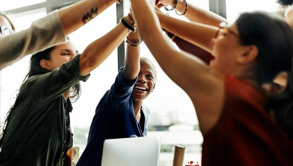 A group of coworkers high-fives to celebrate their music sponsorship in Phoenix.