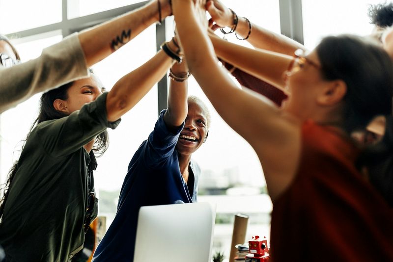 A group of coworkers high-fives to celebrate their music sponsorship in Phoenix.