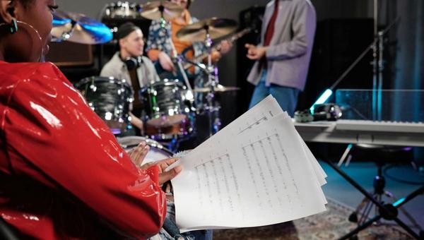 A female singer holding sheet music during band rehearsal as part of a music mentorship program in San Diego.