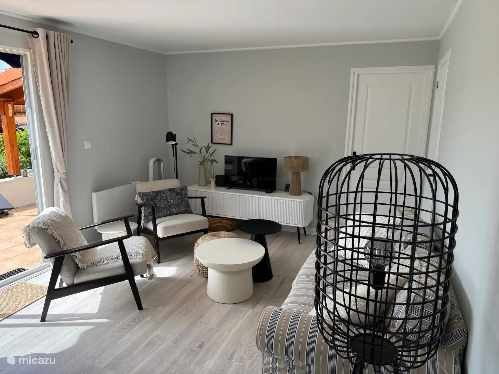 De zithoek van de woonkamer met fauteuils, salontafel en televisie