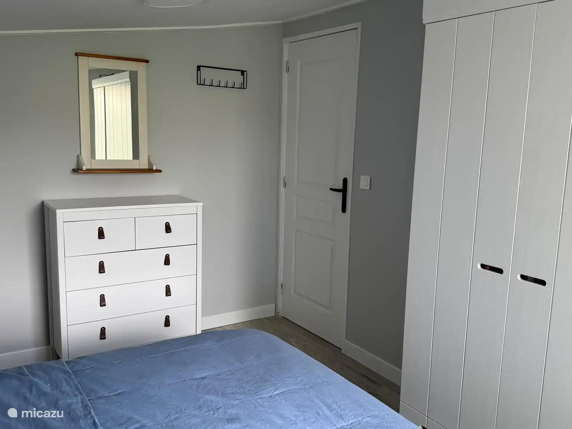 Slaapkamer met een witte kledingkast en een ladekast