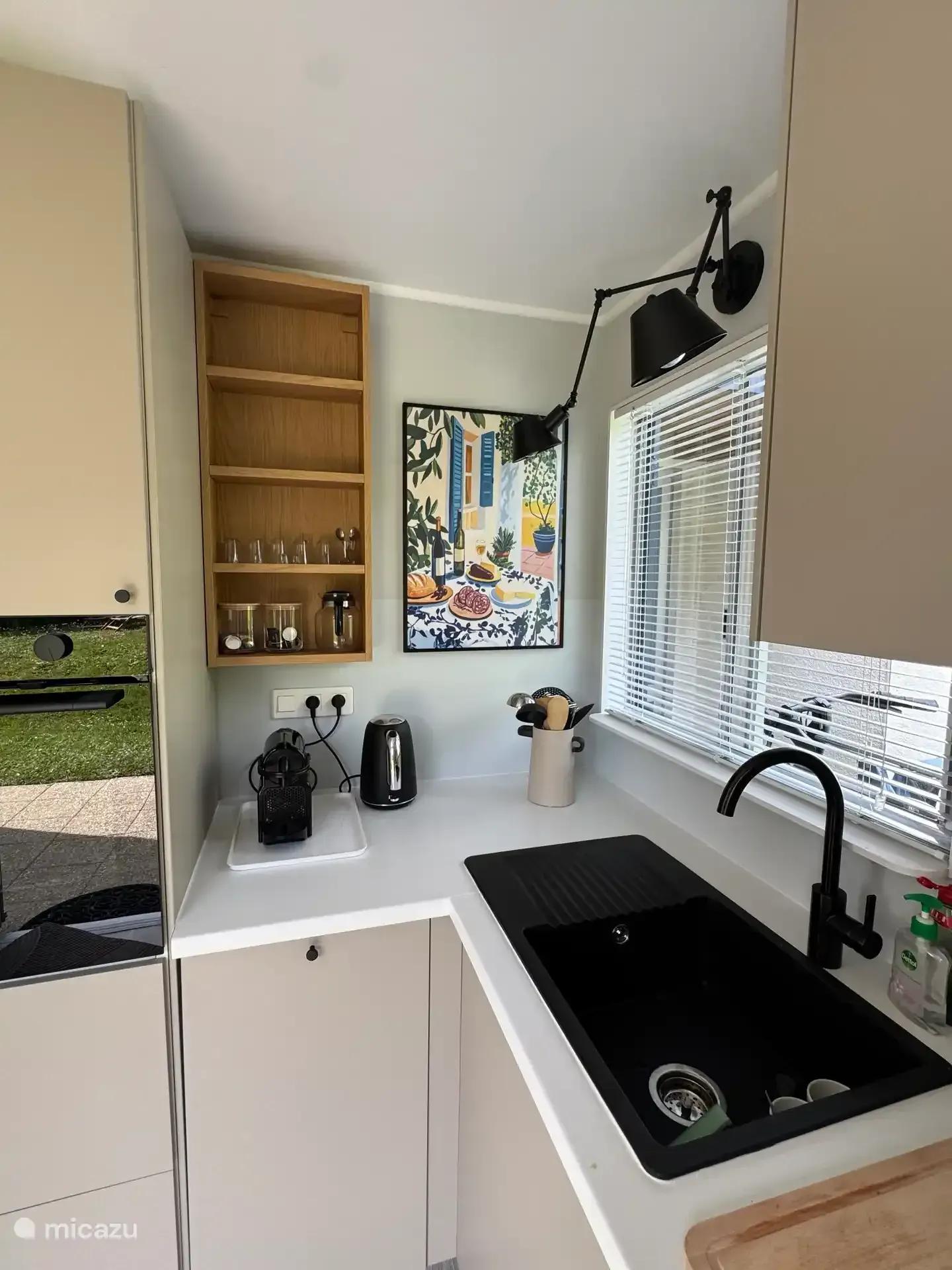 Het aanrecht van de keuken met spoelbak, open planken en keukengerei