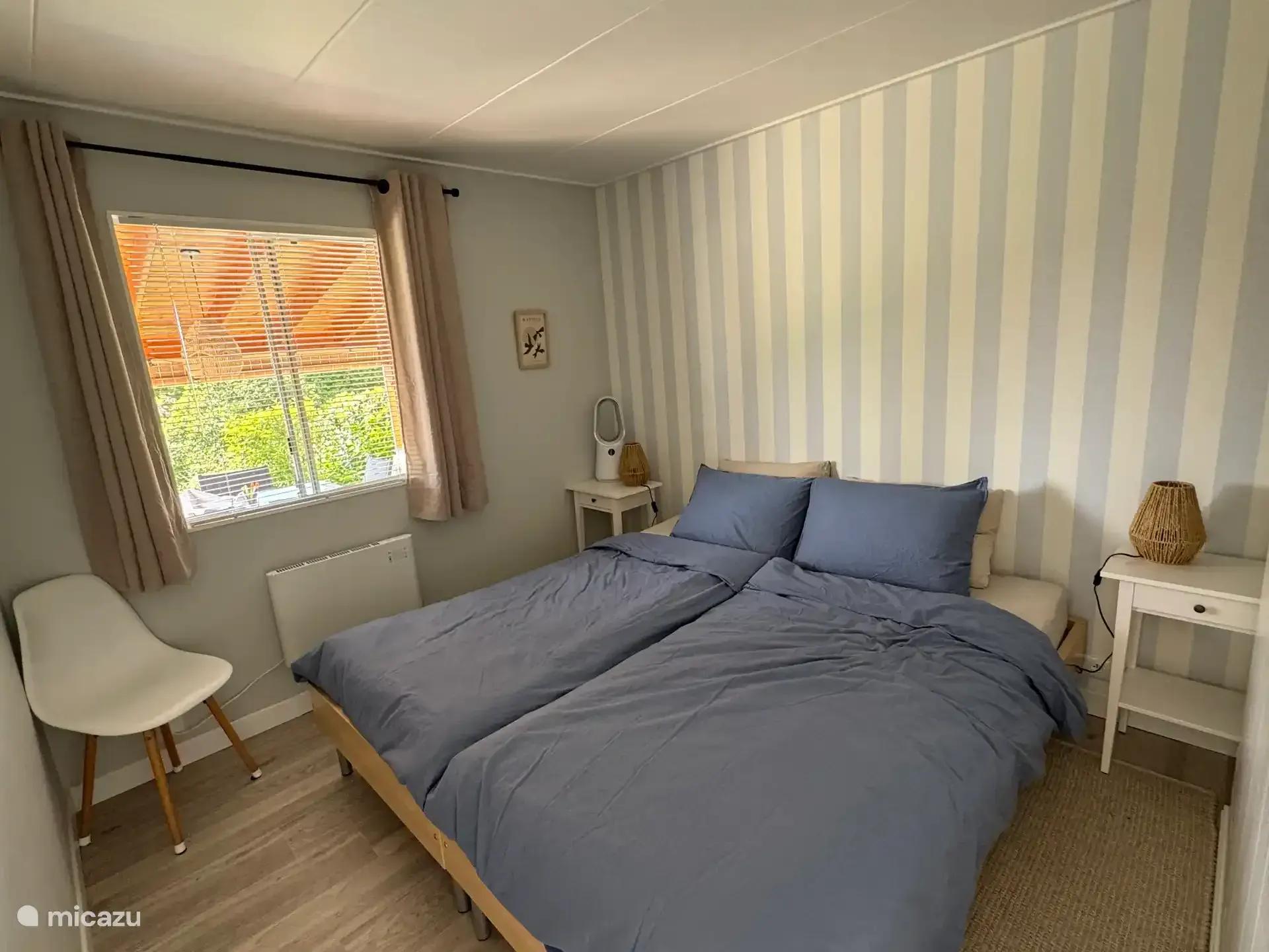 Slaapkamer met tweepersoonsbed en een raam op de tuin