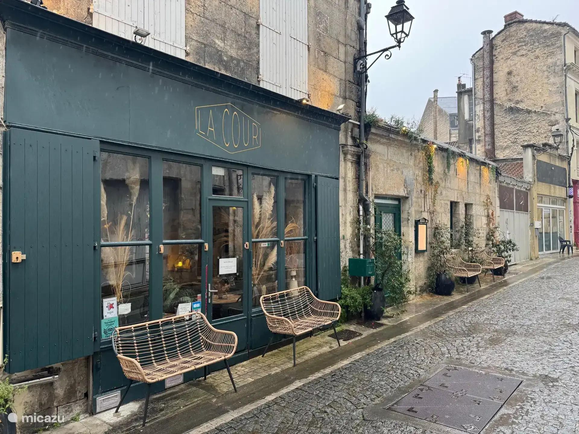 Een café met blauwgroene gevel aan een geplaveide dorpsstraat