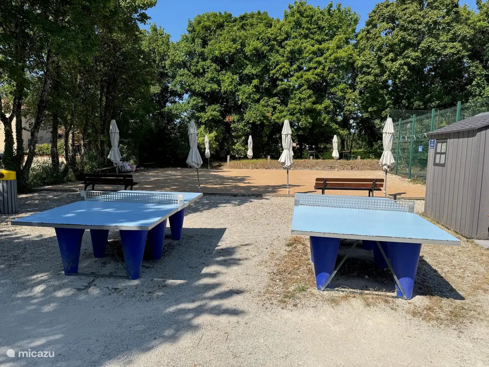 Twee tafeltennistafels op het park, naast de parasols van het terras