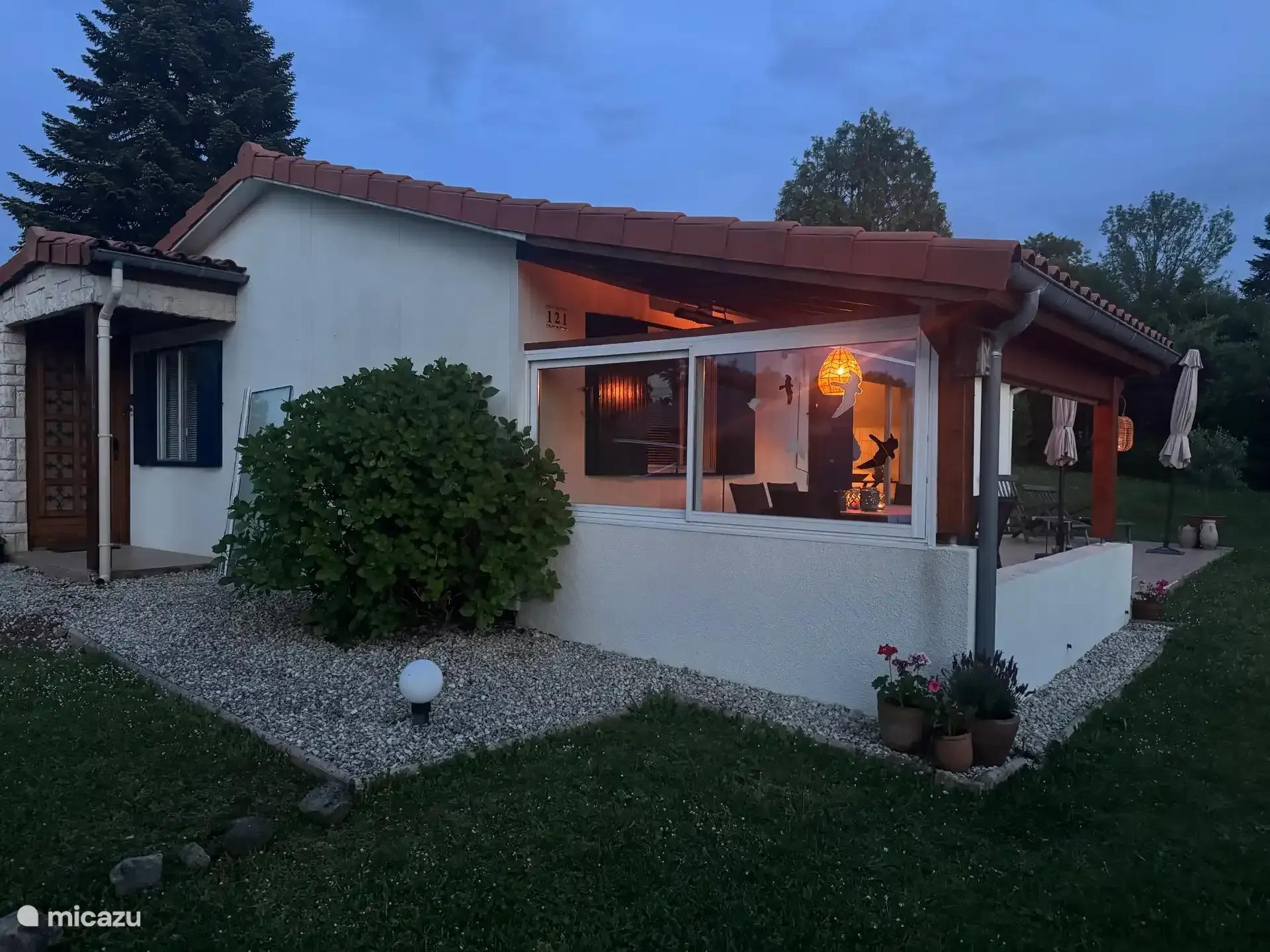 Het huis in de schemering, met verlichting achter de ramen van de serre