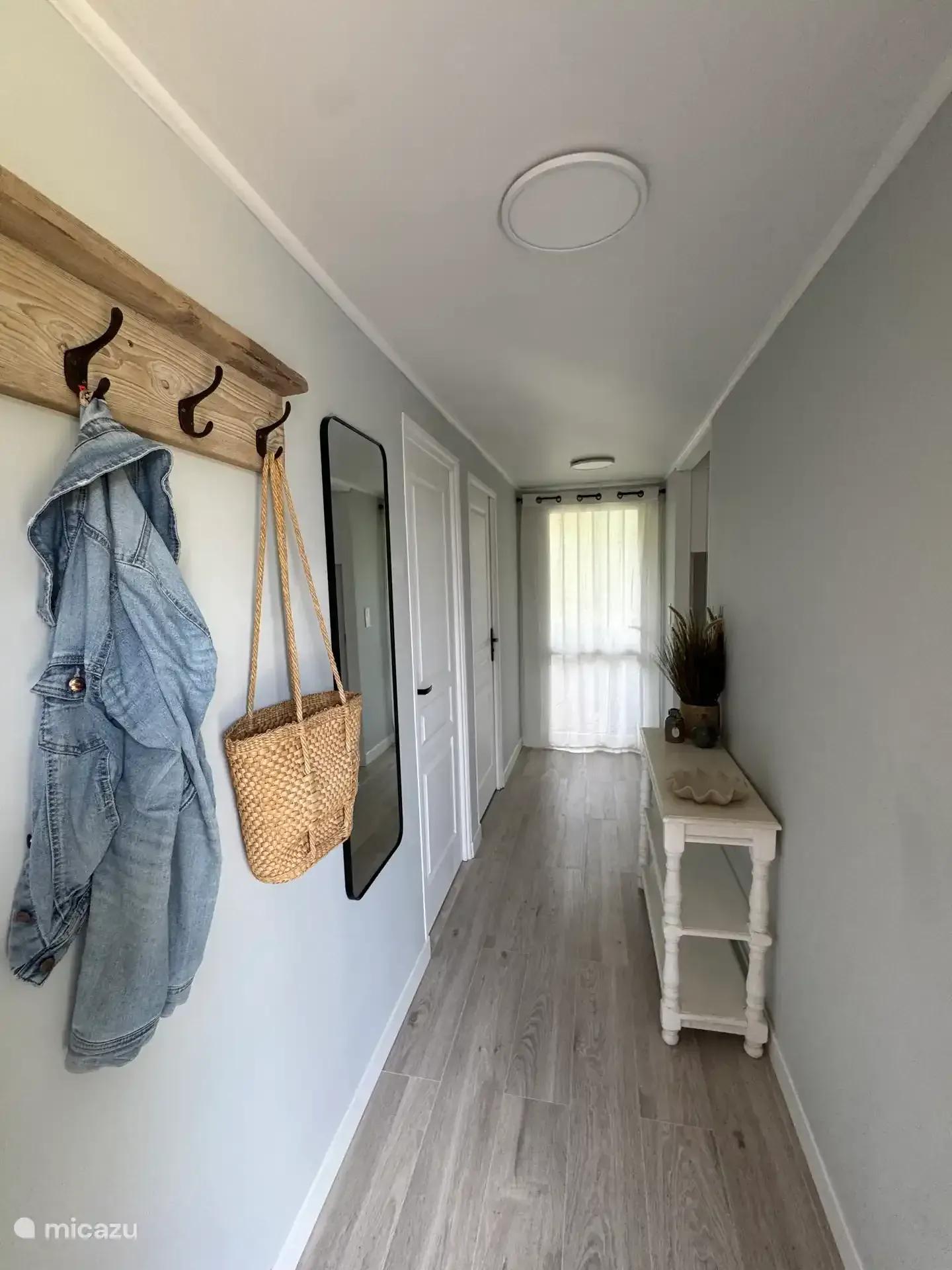 De hal met kapstok en jassen, en zicht op de gang naar de slaapkamers