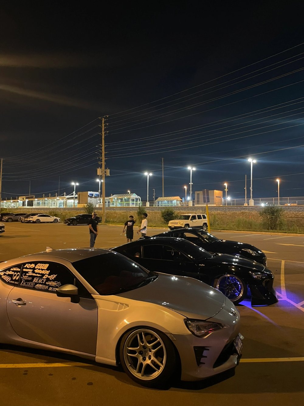 Silver and black coupes lined up under parking-lot lights