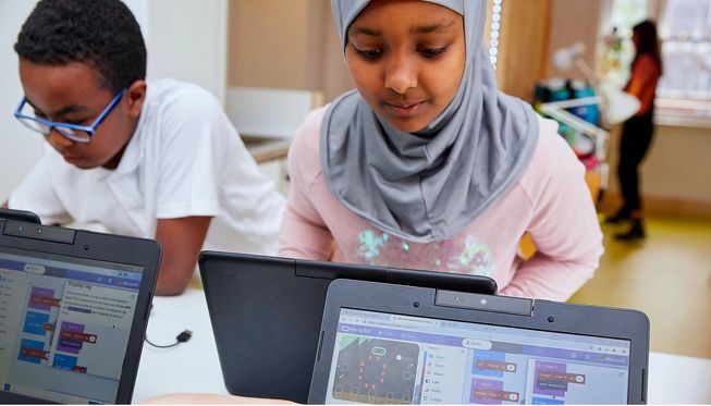 Two children looking at MakeCode on laptop screens