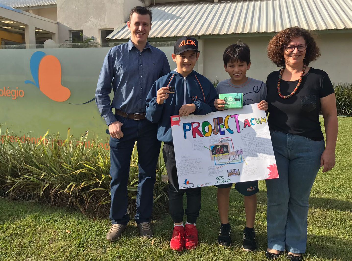 Vinicius y Antonio sostienen el cartel de su diseño a la salida del colegio con sus profesores
