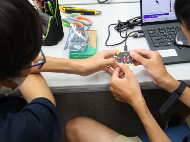 Two students playing with a micro:bit