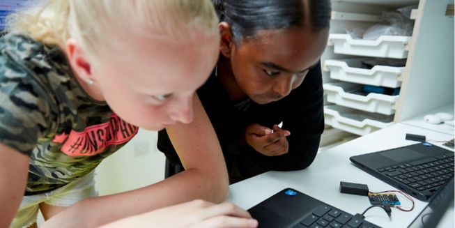 Girls working with a micro:bit and laptops