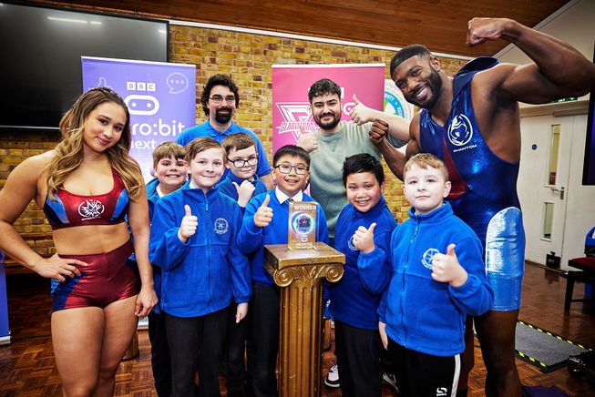 Gladiators Dynamite and Phantom with the winners of the micro:bit Gladiators competition, Our Lady of Lourdes Catholic Primary. Designed by members of the school coding club, The Pugil Puncher is three micro:bit gadgets in one - testing a Gladiator's pugil-stick swinging power and grip strength, with an evaluation of their training sent to a micro:bit smartwatch.