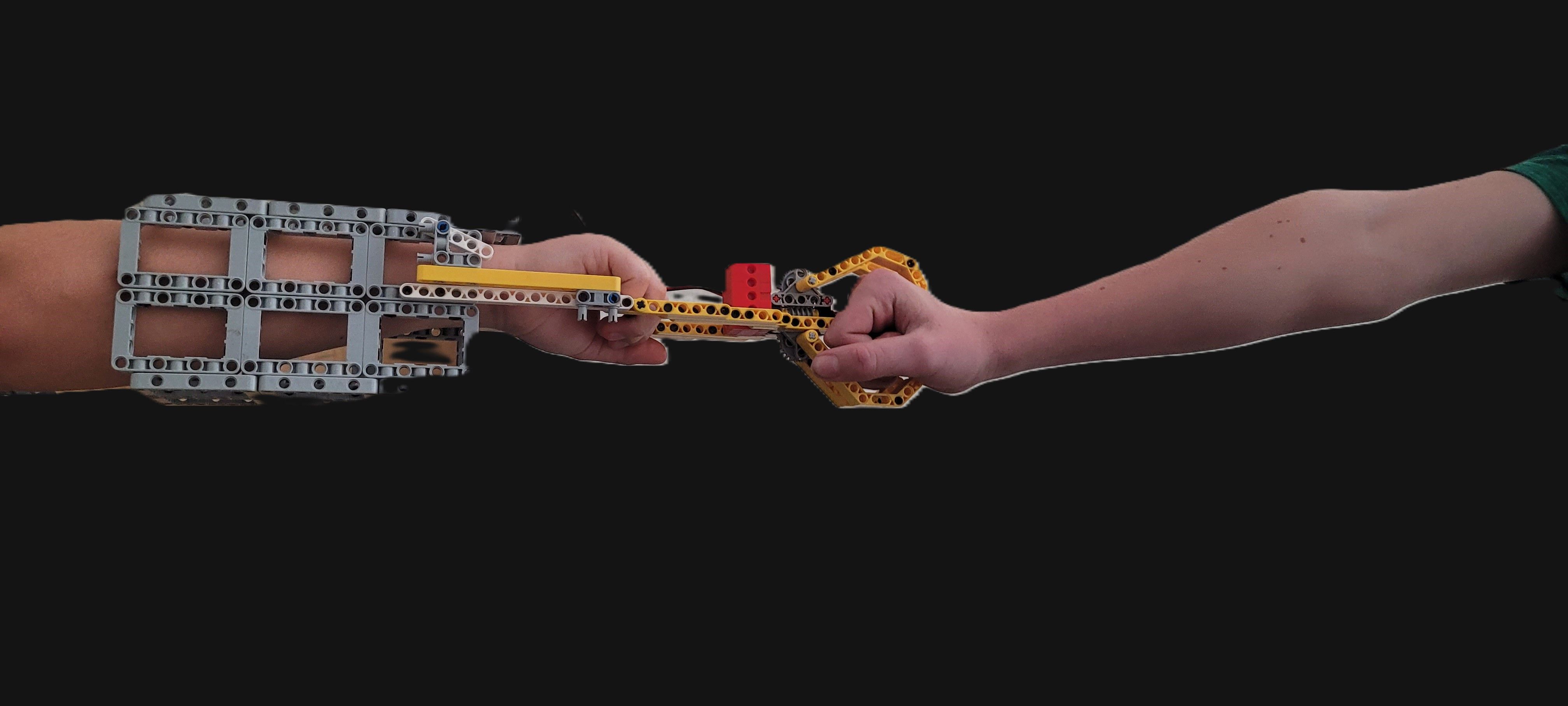 Students fist bump using the robotic arm prototype.