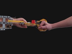 Students fist bump using the robotic arm prototype.