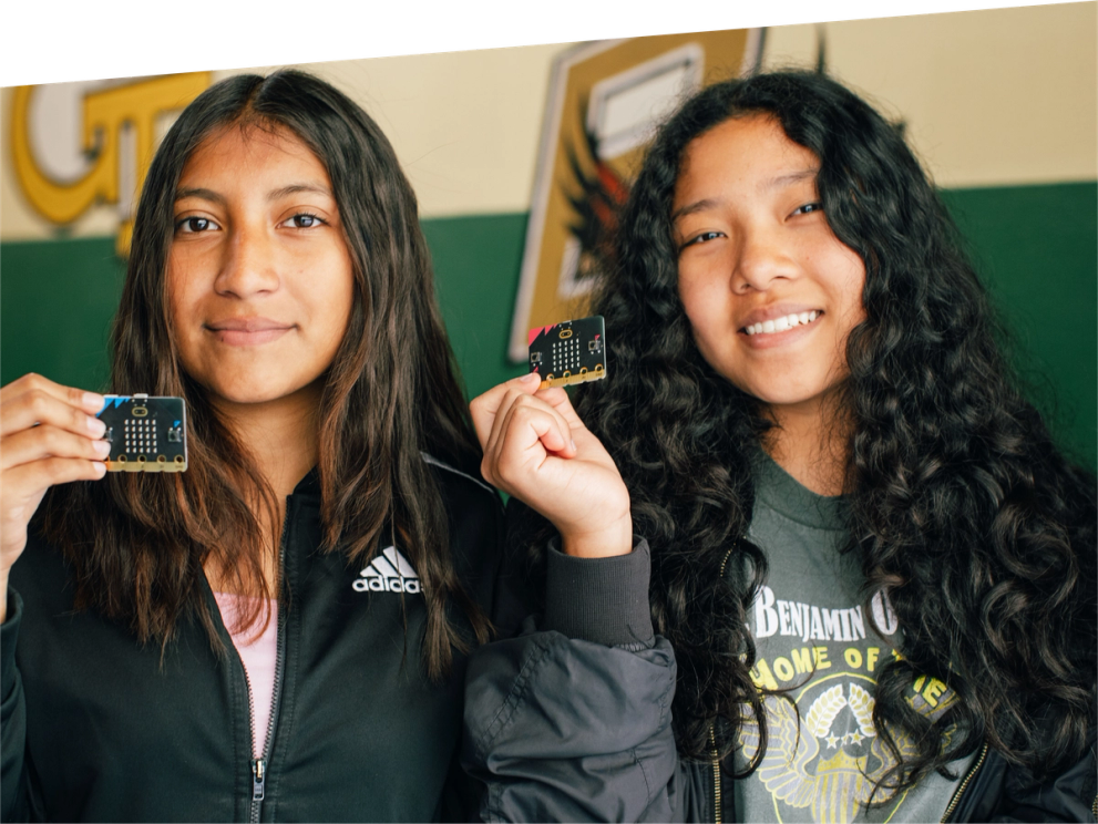 children in class smiling and holding micro:bits