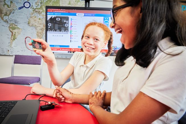 Two girls laughing with their programmed micro:bit