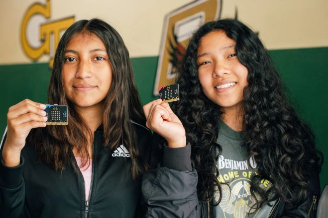 Two female students at Benjamin O Davis Middle School hold up micro:bits proudly