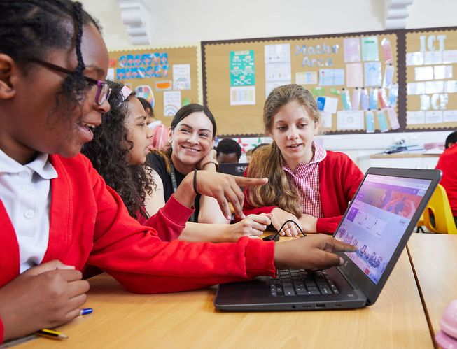 A teacher works with pupils to code their micro:bit