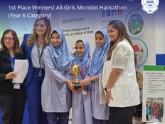 Students smile with their teachers holding an award for their project.
