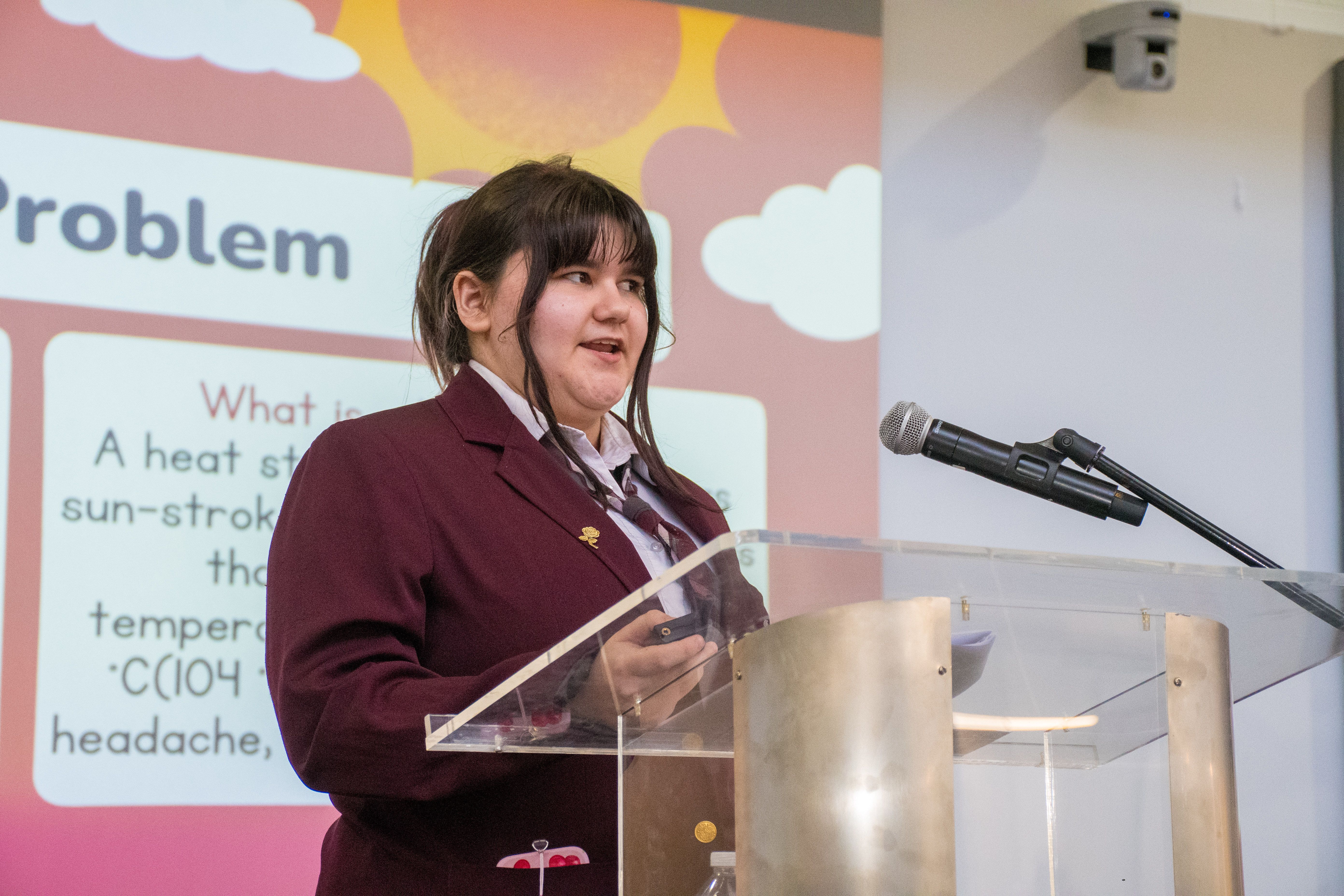 A students stands at a lectern, presenting the Team Cool Down project.