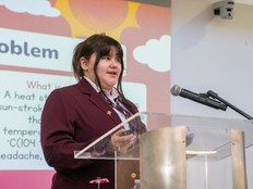 A students stands at a lectern, presenting the Team Cool Down project.