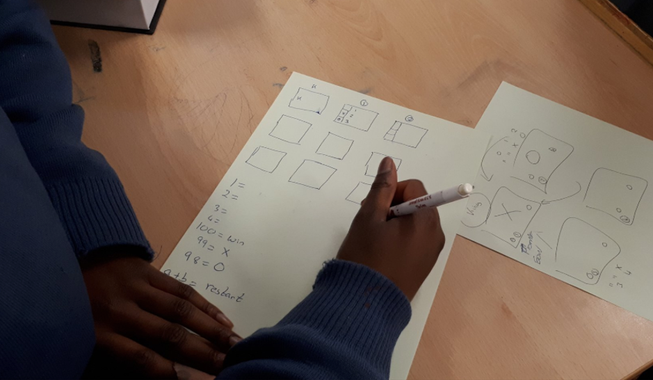 A student drawing a coding activity on paper
